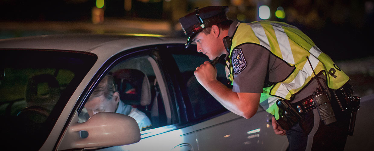 Police officer shines flashlight onto motorist at traffic stop.